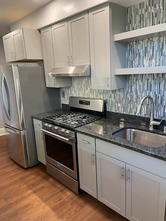 A kitchen with a stainless steel refrigerator, oven, and sink.