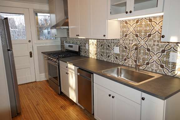 A kitchen with white cabinets and a tile backsplash.