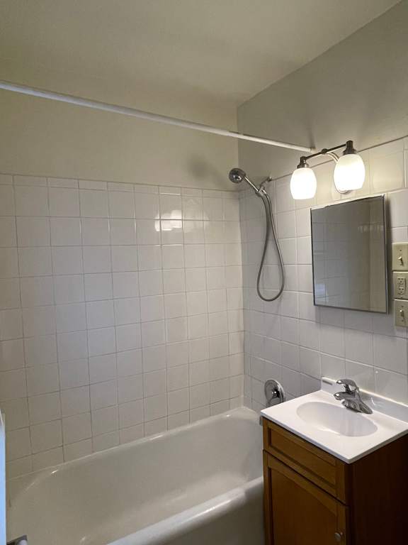 A white tiled bathroom with a white sink and a white bathtub.