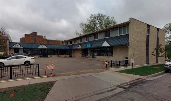 A white car is parked in front of a brick building.