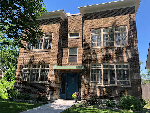 A brick house with a blue door and windows.