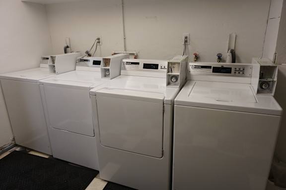 A row of white washing machines in a laundromat.