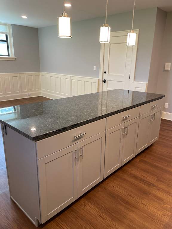A kitchen with a granite countertop and white cabinets.