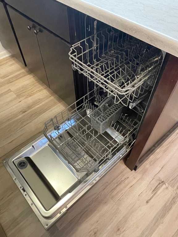 A dishwasher with an open door and a rack of dishes inside.