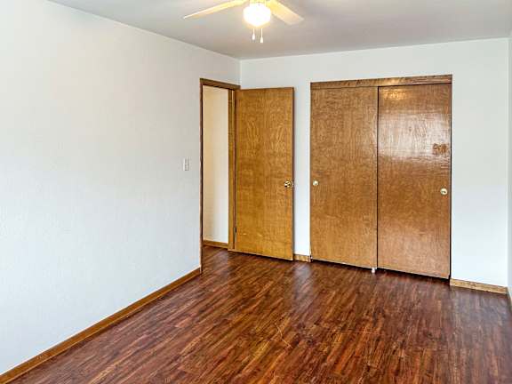 A room with a ceiling fan and three wooden doors.