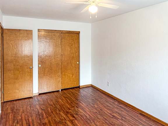 A room with a ceiling fan and two wooden doors.