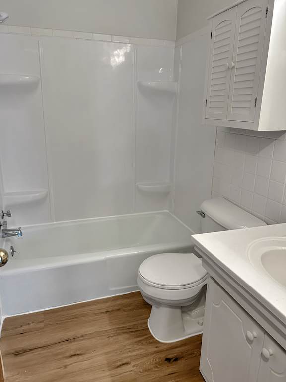 A white toilet sits in a bathroom next to a bathtub.
