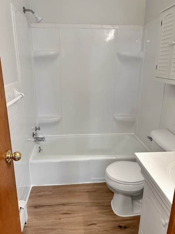 A white toilet sits in a white bathroom with a white tub and a white sink.