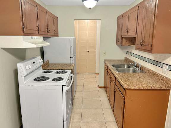 A kitchen with brown cabinets and a white stove.