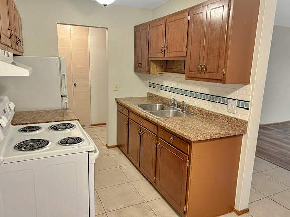 A kitchen with a white stove and brown cabinets.