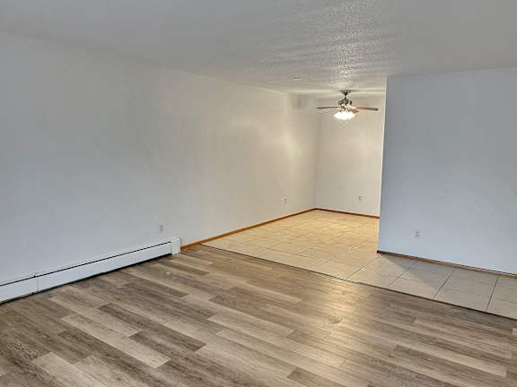 A room with a ceiling fan and wooden flooring.