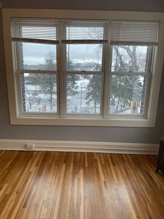 A room with a large window and wooden flooring.