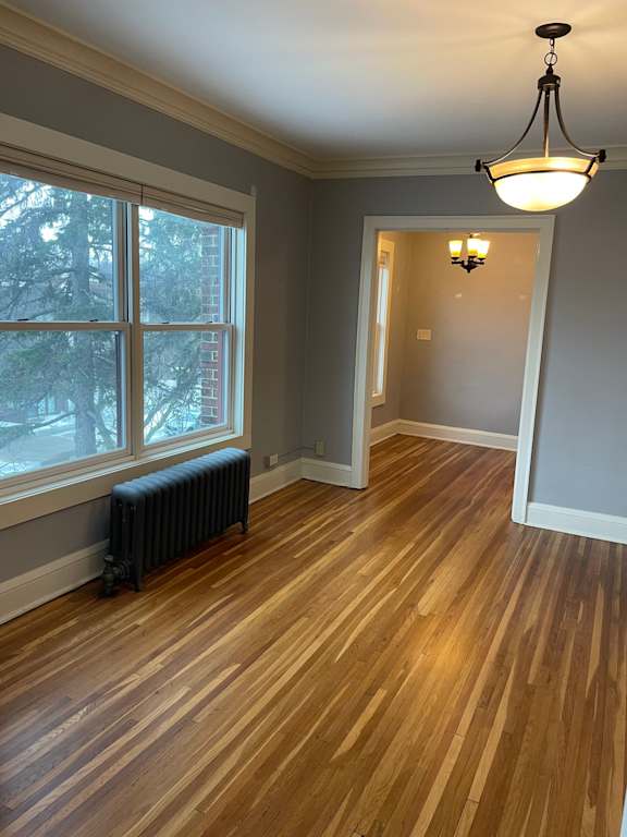A room with wood flooring and a chandelier.