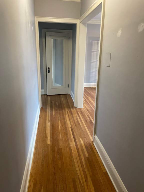 A hallway with a wooden floor and a white door.