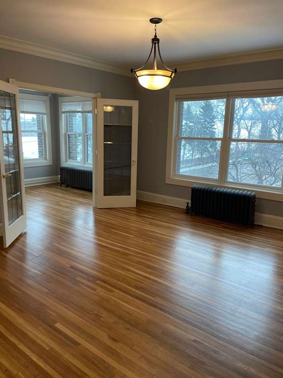 A room with wooden floors and a chandelier hanging from the ceiling.