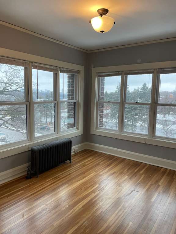 A room with a black radiator and wooden floors.