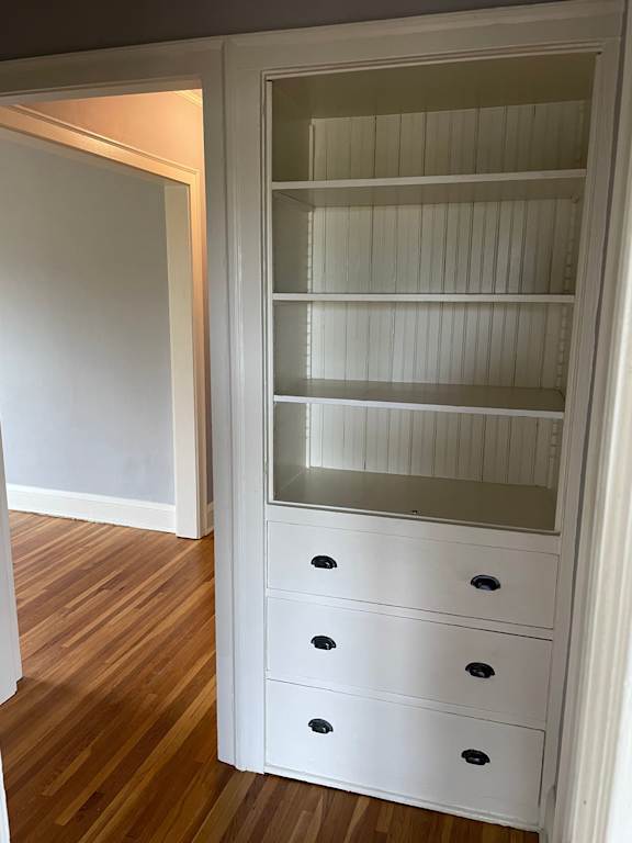 A white cabinet with glass doors and drawers.