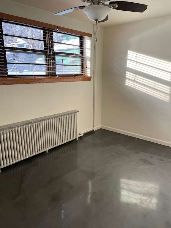 A room with a ceiling fan and a window with blinds.