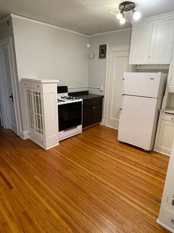A kitchen with a white fridge and wooden floors.