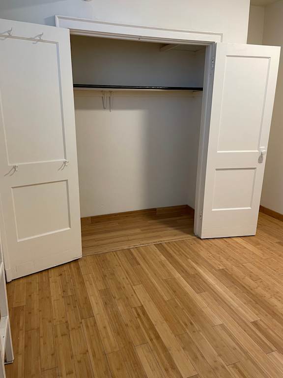 A white closet with a shelf and two doors.