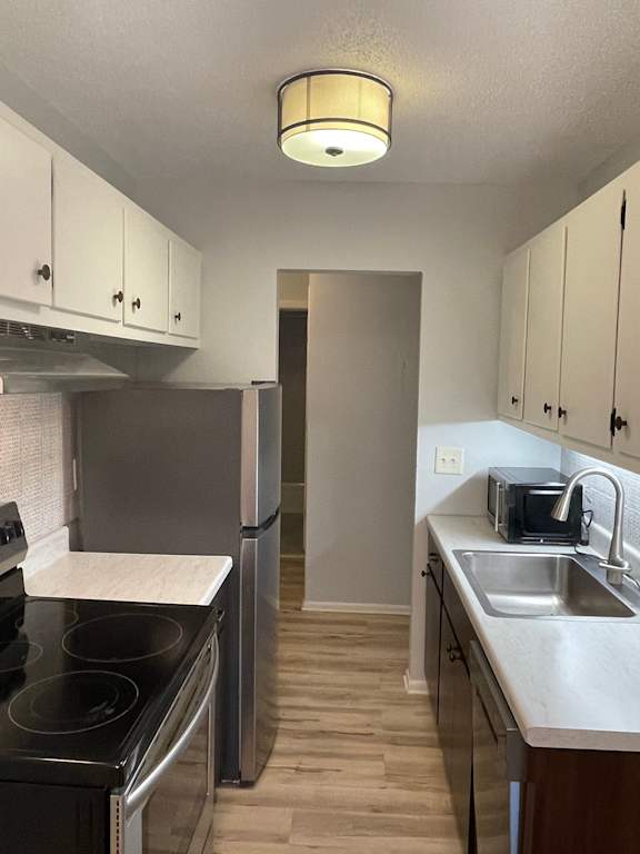 A kitchen with a black stove top oven and a stainless steel refrigerator.