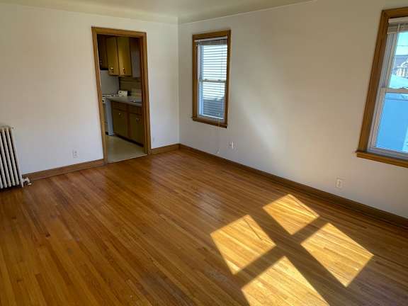 A room with wooden floors and a window with a view of a street.