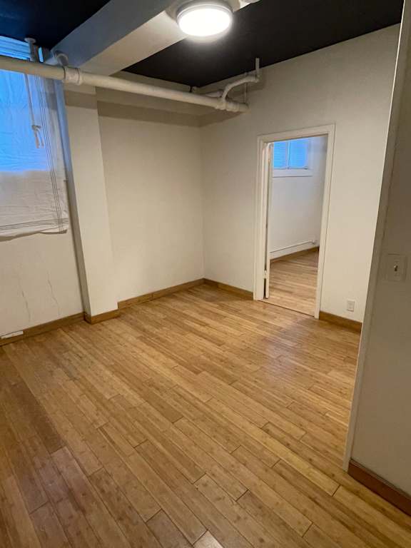 A room with wooden flooring and a window.