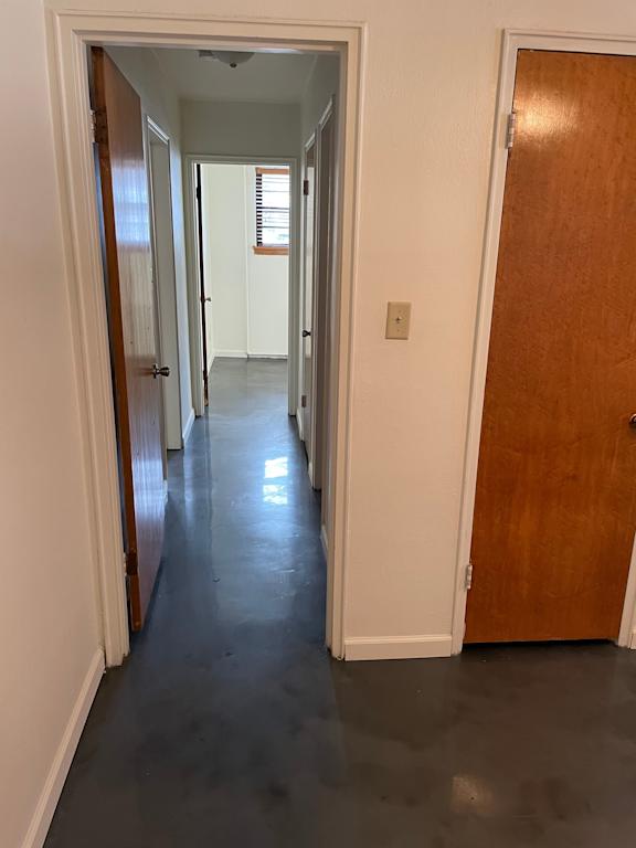 A long hallway with a white door on the left and a brown door on the right.