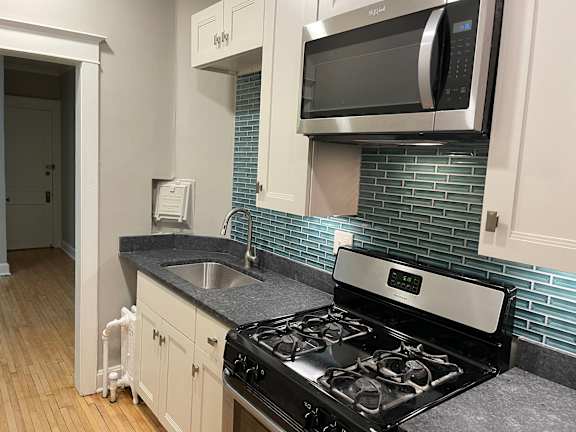 A kitchen with a black stove top oven and a microwave above it.