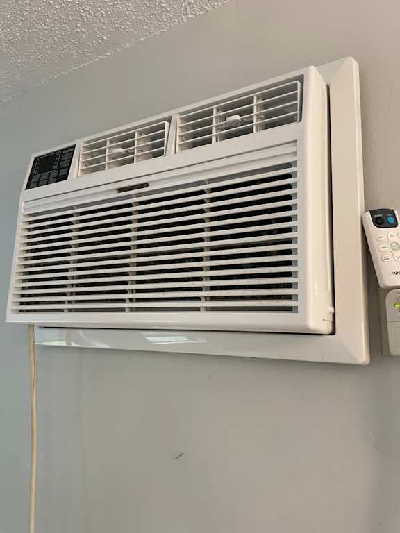 A white air conditioner unit with a remote control attached to it.