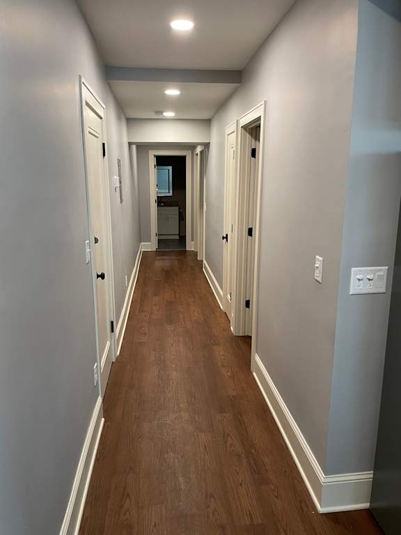 A long hallway with doors on both sides and a light switch on the wall.