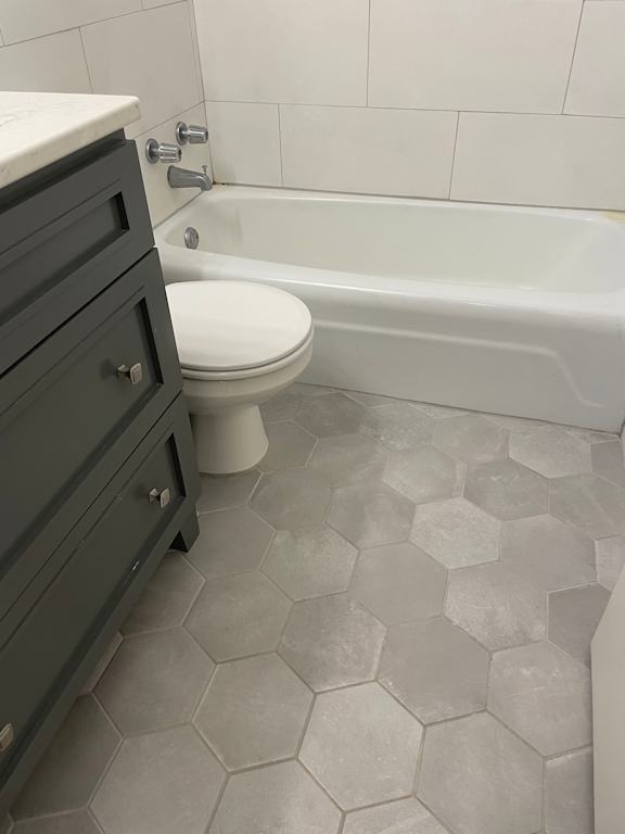 A white toilet sits next to a bathtub in a bathroom.