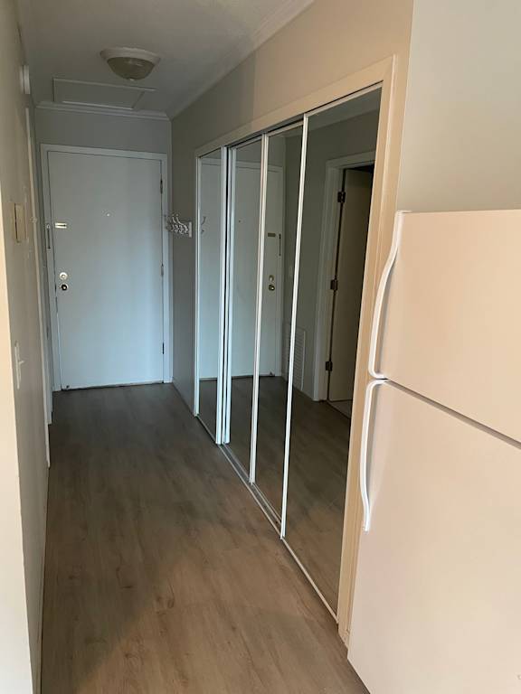 A white door is open in a hallway with wood floors.