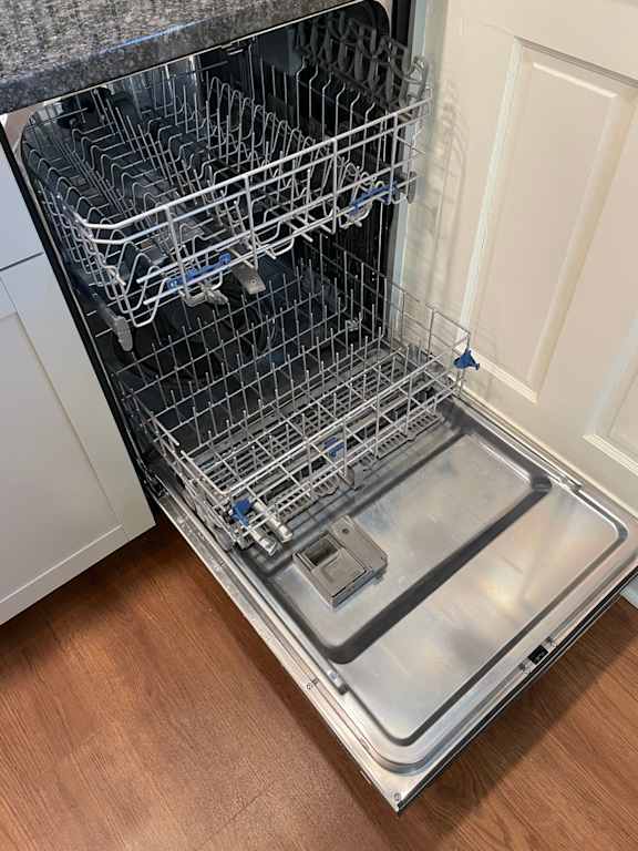 A dishwasher with the door open and racks inside.
