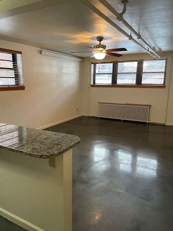 A room with a fan, window, and radiator.