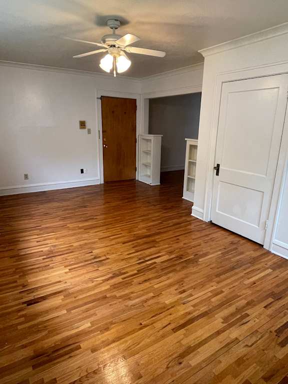 A room with a ceiling fan and wooden floors.