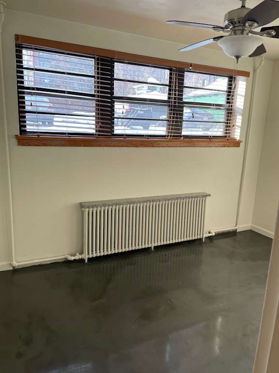 A room with a ceiling fan and a window with blinds.
