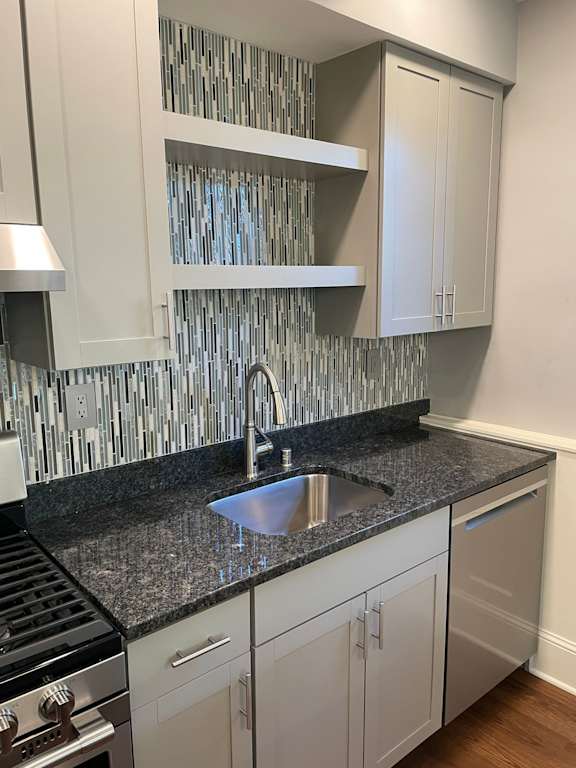 A kitchen with a granite countertop and white cabinets.