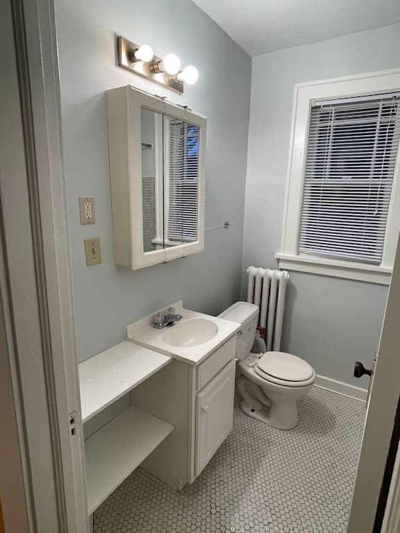 A white bathroom with a toilet, sink, and mirror.