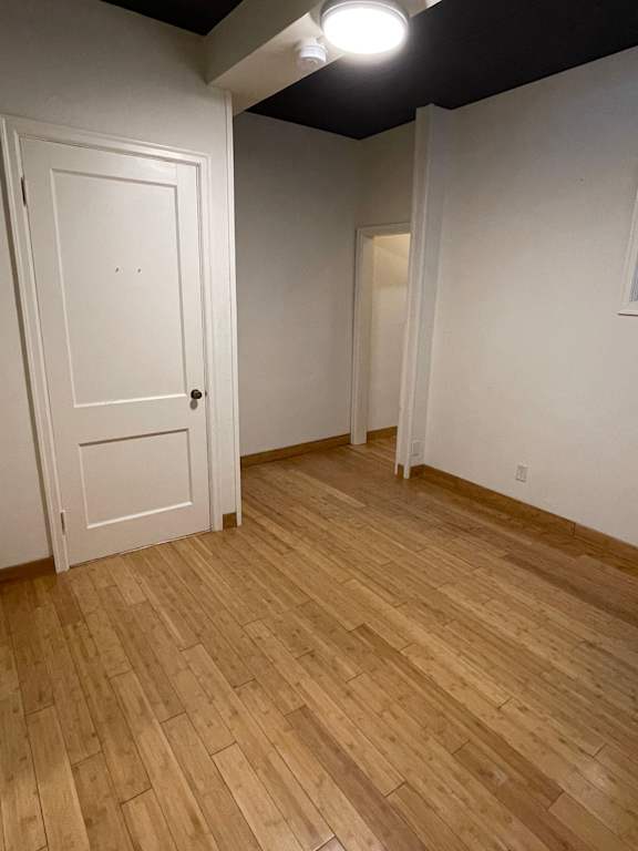 A room with a white door and wooden flooring.