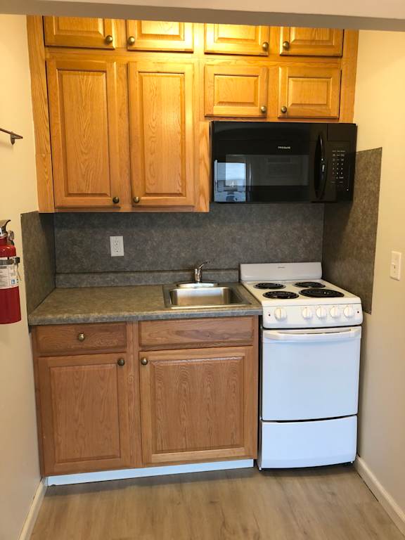 A kitchen with wooden cabinets and a white stove.