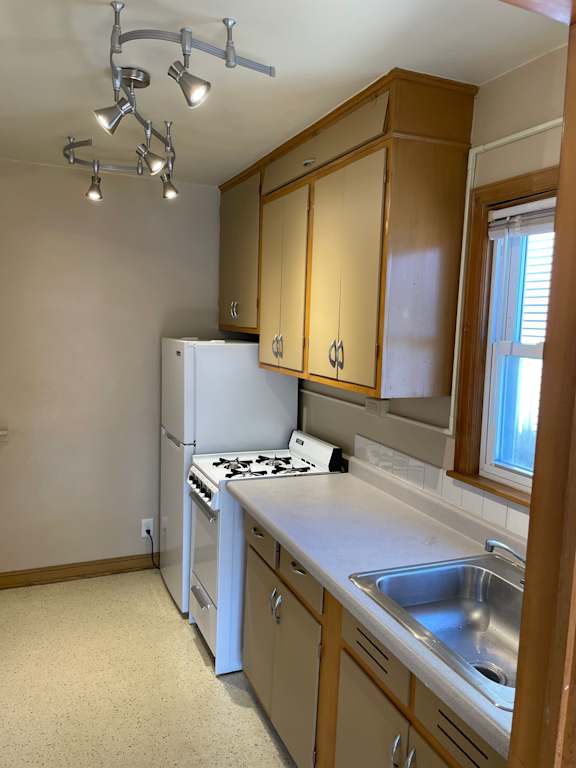 A kitchen with a white refrigerator and a sink.