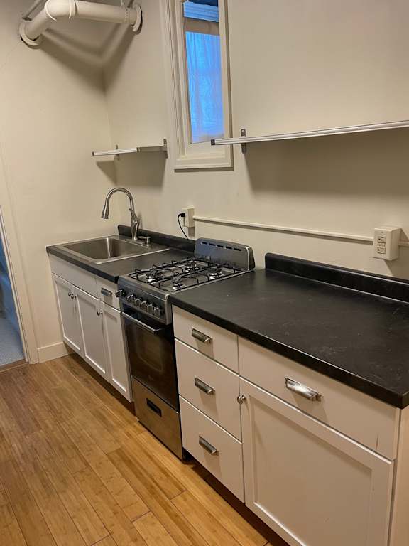 A kitchen with white cabinets and a black countertop.