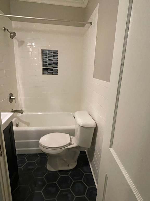 A white toilet in a small bathroom with a black hexagonal tile floor.