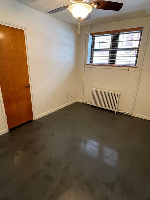 A room with a ceiling fan and a window with blinds.