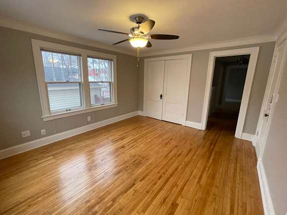 A room with a ceiling fan and wooden flooring.