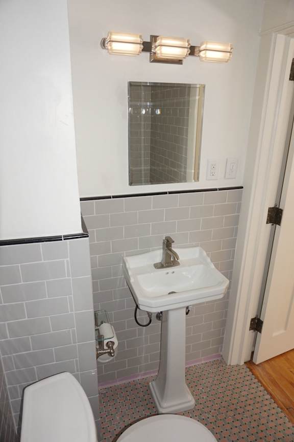 A white sink with a pedestal and a toilet in a bathroom.