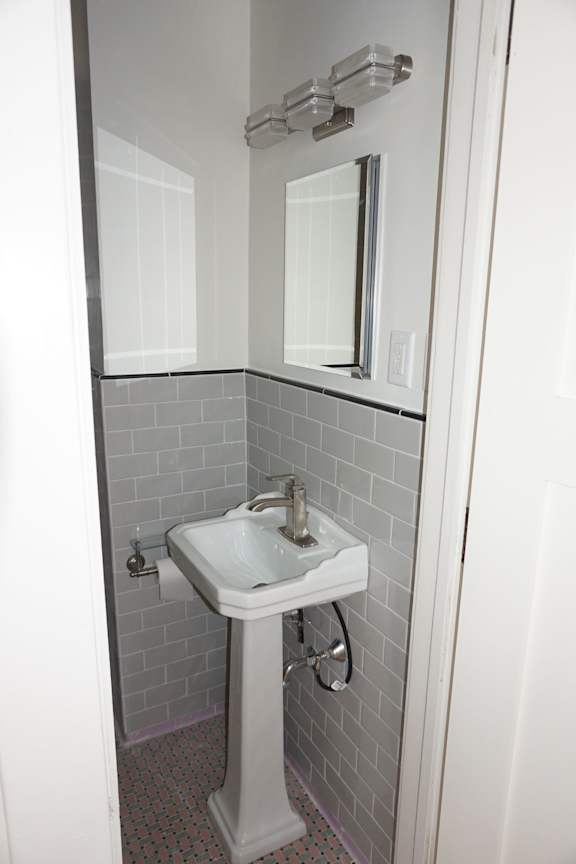 A white pedestal sink in a tiled bathroom.