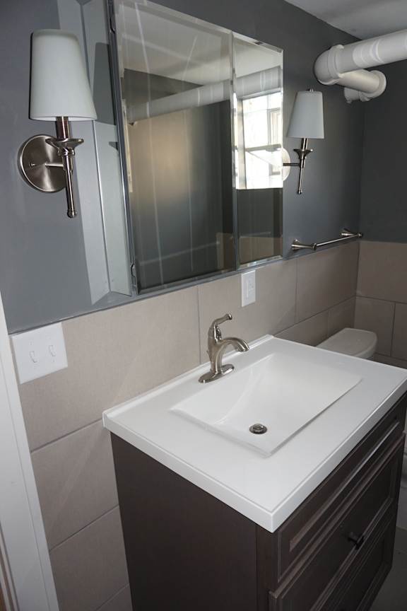 A white sink in a bathroom with a brown counter top.