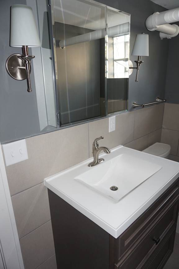 A white sink in a bathroom with a mirror above it.
